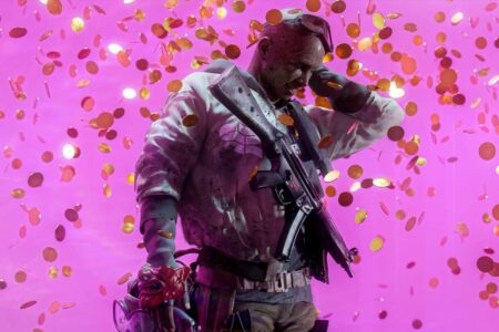 The Finals contestant standing against a pink wall with shower of coins on him