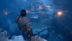 The main character is standing on a cliff, looking over at a burning village