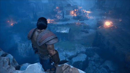 The main character is standing on a cliff, looking over at a burning village