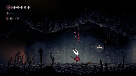 A screenshot of Hornet standing below Rosary strings in Hollow Knight Silksong